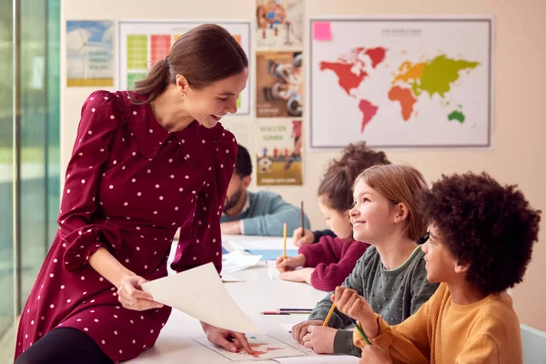 Uśmiechnięta Nauczycielka Szkoły Podstawowej Pracująca Przy Biurku Klasie Uczniami — Zdjęcie stockowe