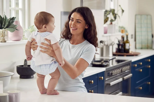 一緒に台所で家の中で赤ちゃんの息子の世話を愛する母親 — ストック写真