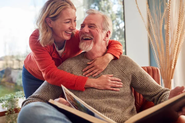 Uśmiechnięta Para Seniorów Domu Ciesząca Się Wspólnym Oglądaniem Albumu Fotograficznego — Zdjęcie stockowe