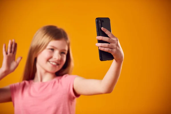 在黄色背景下 少女在手机上自拍的工作室肖像 — 图库照片