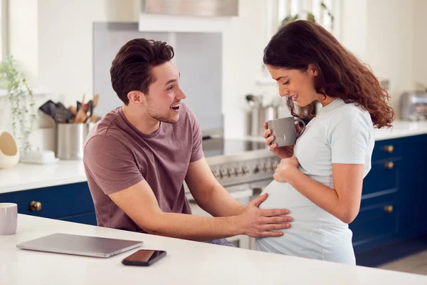 女性の胃に触れる男と一緒にキッチンで自宅で興奮妊娠性転換カップル — ストック写真