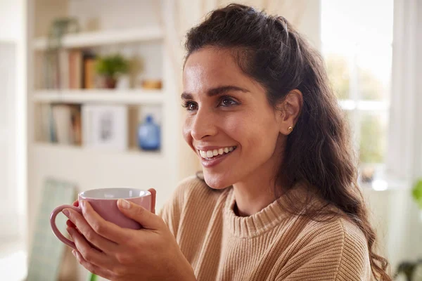 Woman Relaxing At Home Sitting At Table With Hot Drink