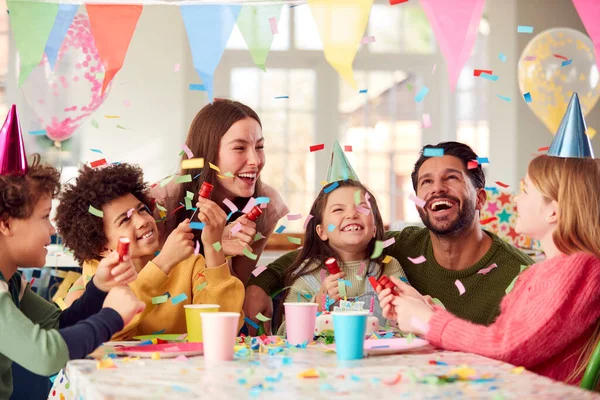 パーティーでお祝いの誕生日のお祝いのお菓子のポッパーで両親や友人と女の子 — ストック写真