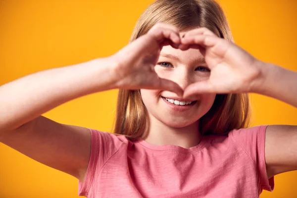 Studio Portrait Smiling Girl Making Heart Shape Hands Yellow Background — Stock Photo, Image