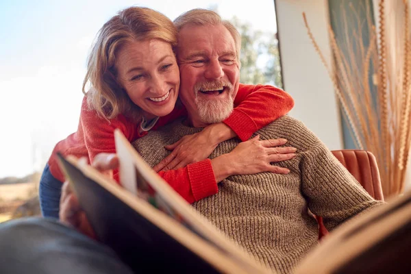 Uśmiechnięta Para Seniorów Domu Ciesząca Się Wspólnym Oglądaniem Albumu Fotograficznego — Zdjęcie stockowe