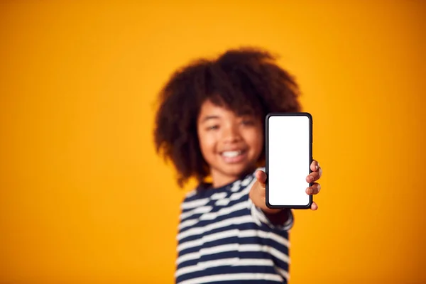 黄色の背景にソーシャルメディア画面で携帯電話を示す少年のスタジオの肖像画 — ストック写真