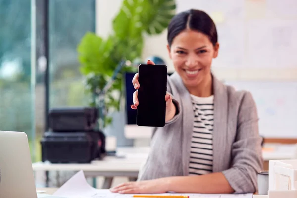 女性建筑师在办公室工作的肖像 手握手机坐在办公桌前对着相机 — 图库照片