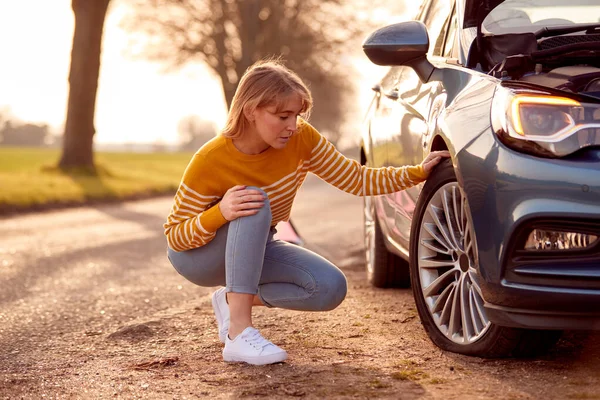 Žena Porouchaná Venkovské Silnici Kontroluje Auto Pneumatiky Pro Propíchnutí — Stock fotografie