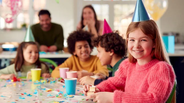 自宅で両親や友人とパーティーで誕生日ケーキを食べる女の子の肖像 — ストック写真