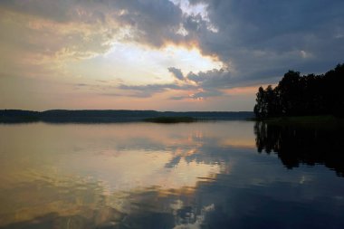 Orman gölünün üzerinde güzel bir gün batımı. Rüzgarsız bir akşam. Ufuk. Yansıma. Renk ve ışık simetrisi.                                