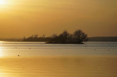  Kuş Adaları Gölü üzerinde gün batımı. Bahar Nisan. Su kuşu. Yansıma. Ufuk.                              