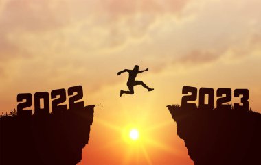 2022 ile 2023 yılları arasında genç bir siluet adam güneşin üzerinden ve tepedeki akşam gökyüzünün boşluğundan atlıyor. İş konsepti. Hoş geldiniz. Mutlu yıllar 2023. Vektör illüstrasyonu.