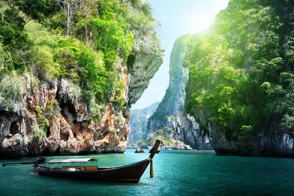 Barco longo e rochas na praia ferroviário em Krabi, Tailândia Imagem De Stock