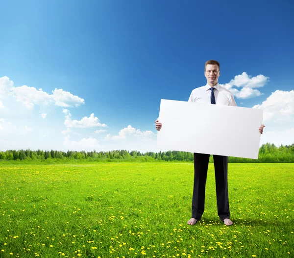 Business man whith empty board in hand on the field of spring grass — стоковое фото