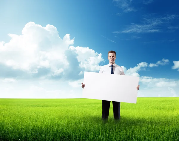 Hombre de negocios con tablero vacío en la mano en el campo de hierba de primavera — Foto de Stock