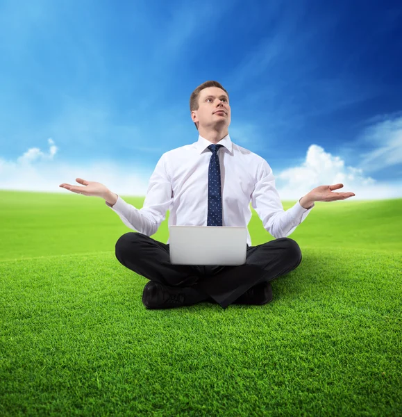 Business man with notebook sitting on grass — Stock Photo, Image