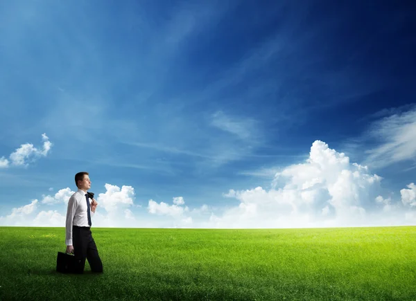 Joven hombre de negocios wolking en el campo de hierba — Foto de Stock