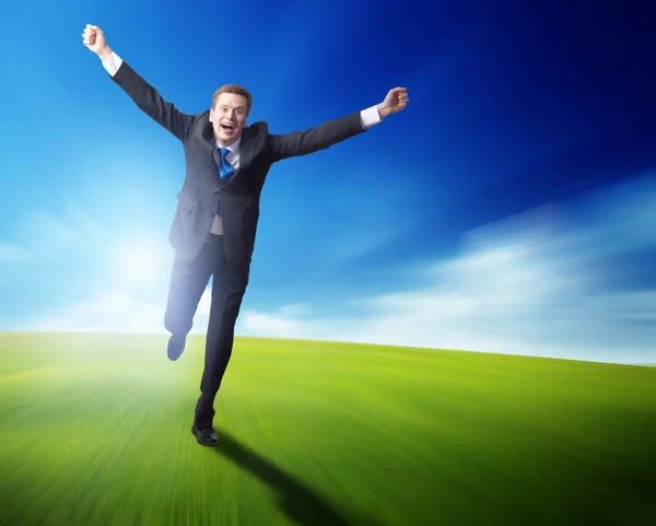 Homem de negócios feliz correndo no campo de mola azul — Fotografia de Stock