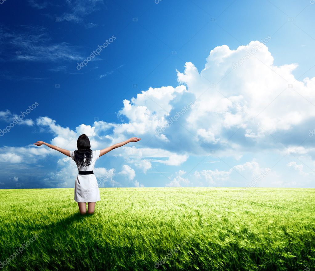 Happy young woman in white dress standing in field