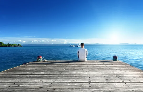 Jeune homme se détendre assis sur le quai — Photo