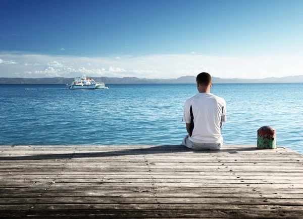 Mladý muž relaxovat, sedící na molu — Stock fotografie