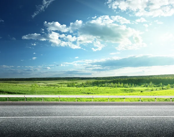 Asphalt road and perfect green field — Stock Photo, Image