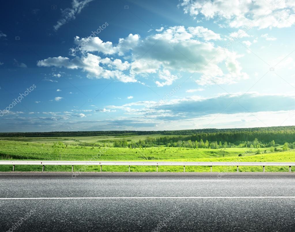 asphalt road and perfect green field