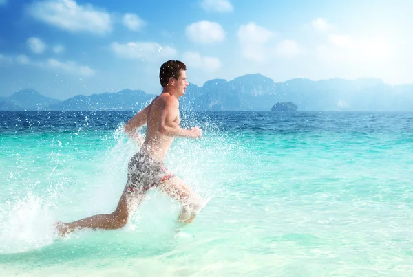Homem correndo na água do mar tropical — Fotografia de Stock