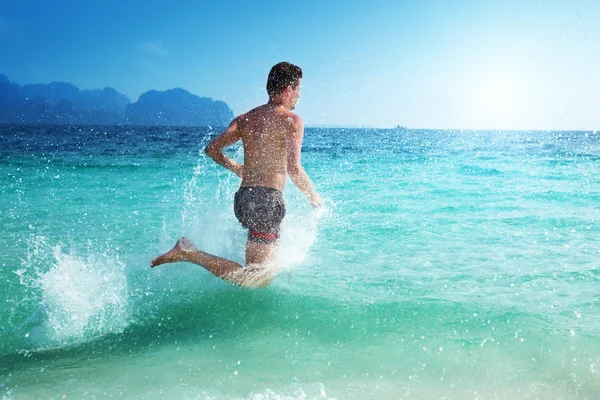 Homem correndo na água do mar tropical — Fotografia de Stock