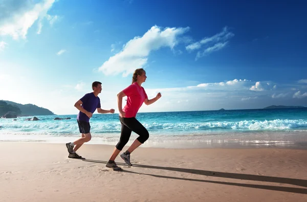 Hombre y mujeres corriendo en la playa tropical al atardecer —  Fotos de Stock