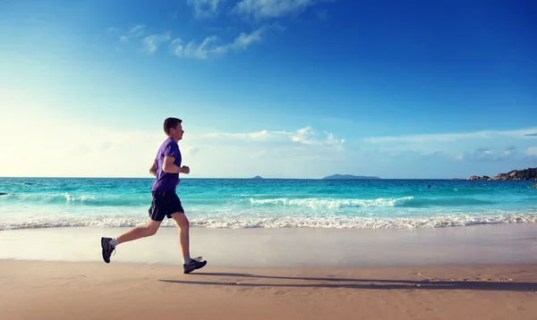 Homme courant sur la plage tropicale au coucher du soleil — Photo