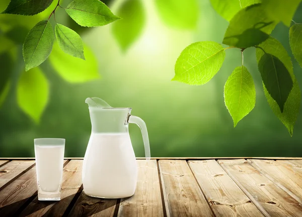 Leche sobre la mesa y árboles soleados — Foto de Stock