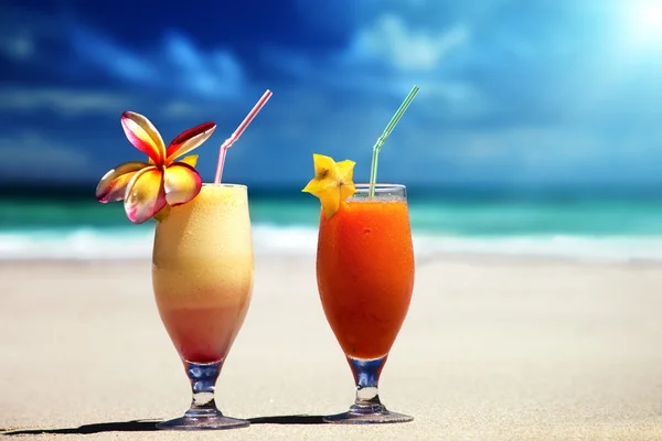 Свежие фруктовые соки на тропическом пляже — стоковое фото