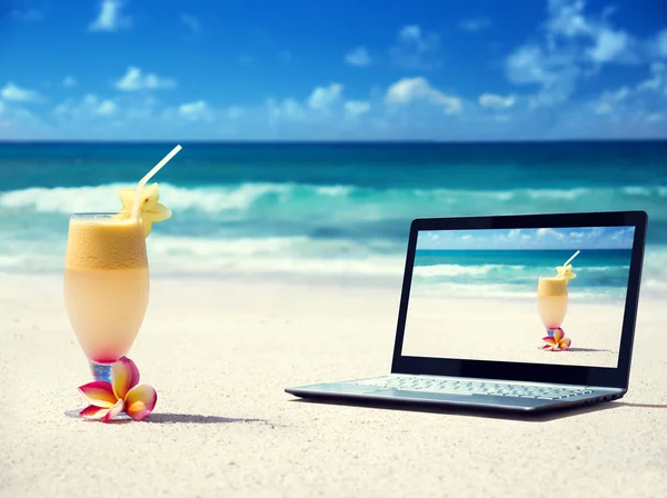 Portátil en la playa y un vaso de jugo fresco — Foto de Stock