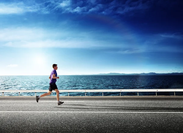 Courir jeune homme et océan au coucher du soleil — Photo