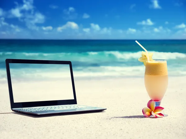 Portátil en la playa y un vaso de jugo fresco — Foto de Stock