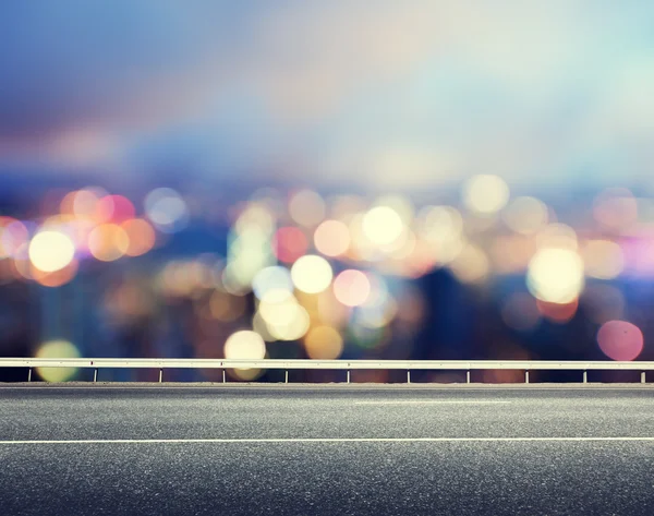 Asphalt road and blurred modern city — Stock Photo, Image