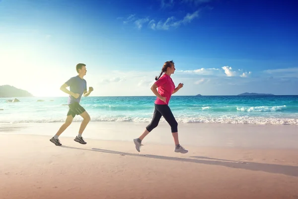 Hombre y mujeres corriendo en la playa tropical al atardecer —  Fotos de Stock