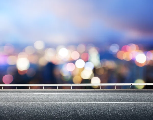 Asphaltstraße und verschwommene moderne Stadt — Stockfoto