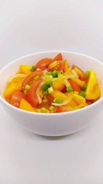 Beyaz arka planda beyaz bir kasede taze domates salatası.