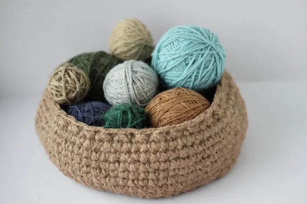 Skeins of colored yarn in a jute basket on a white background isolate
