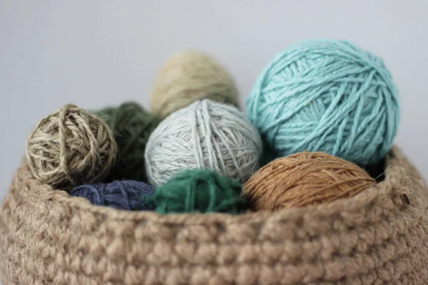 Skeins of colored yarn in a jute basket on a white background isolate