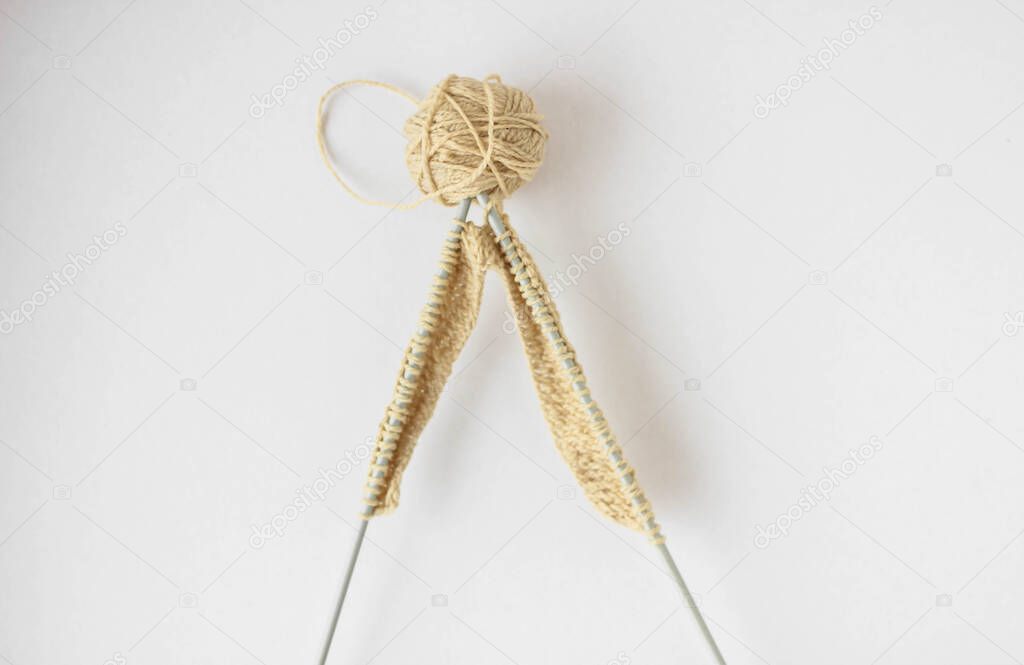 Top view beige yarn and knitting needles on a white background isolated