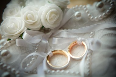 Two wedding rings with white flower in the background. clipart