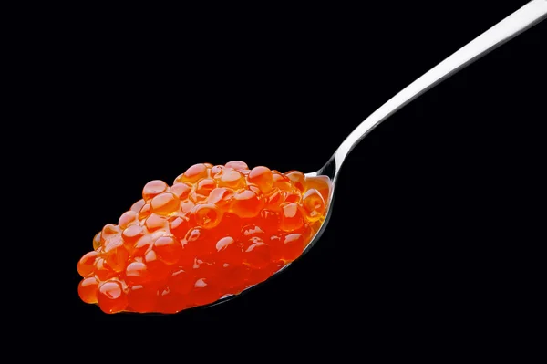 The spoon with red caviar on a black background — Stock Photo, Image