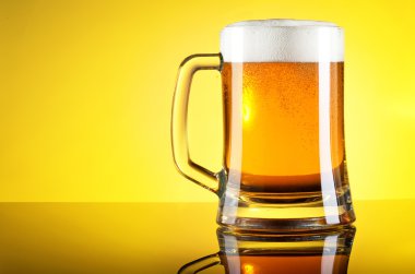 bira yakın çekim ile sarı zemin üzerinde köpük bardak