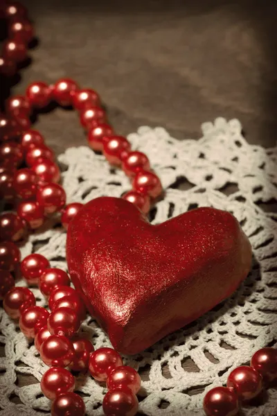 Глиняное сердце и бусы на трикотажной ткани — стоковое фото