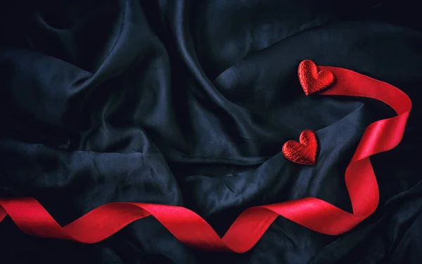 两颗红心和缎带在黑色丝绸上 情人节卡片 顶部视图 — 图库照片