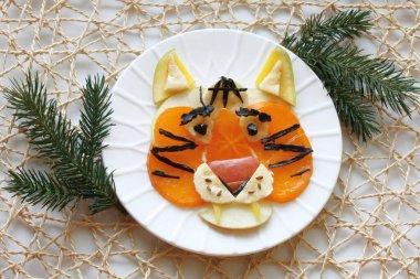 Beyaz tepside meyvelerden yapılmış kaplan yüzü, Çin yeni yılı, çocuk menüsü, üst manzara.