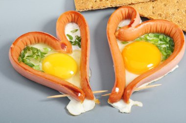Two sausages in a heart-shaped fried eggs.